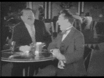 two men in suits are sitting at a table in a restaurant