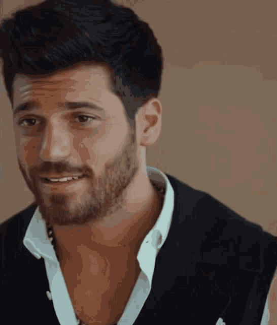 a man with a beard wearing a white shirt and black vest