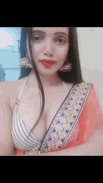 a woman is wearing a bra and a red saree and earrings .