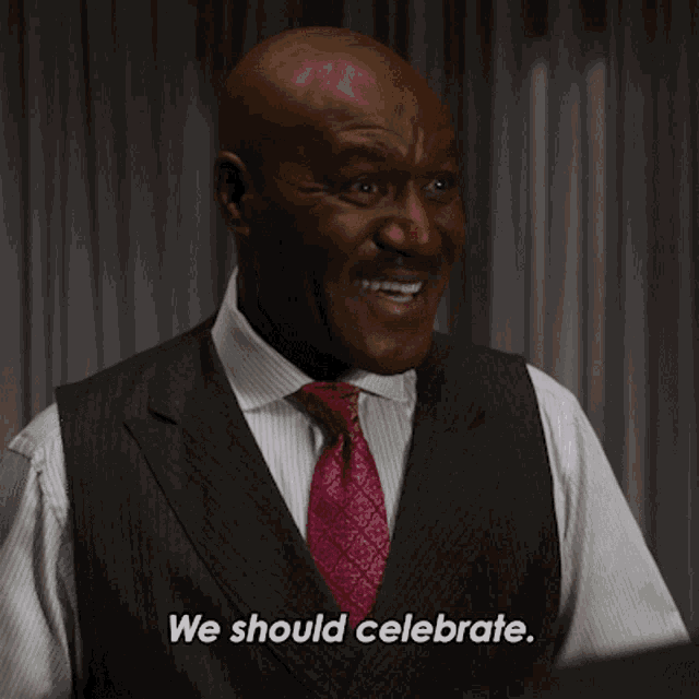 a bald man in a suit and tie says we should celebrate