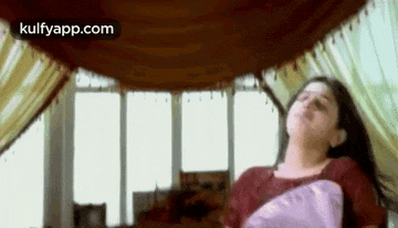 a woman is laying on a bed with her eyes closed and a pillow .