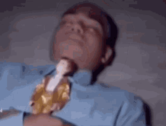 a man in a blue shirt holds a doll in his mouth .