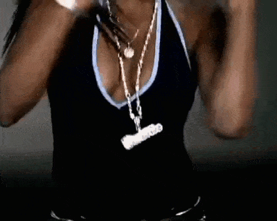 a woman is wearing a black tank top with a plunging neckline and a gold chain around her neck .