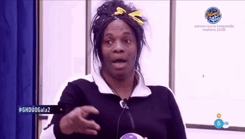 a woman in a black and white sweater is holding a ball and making a funny face