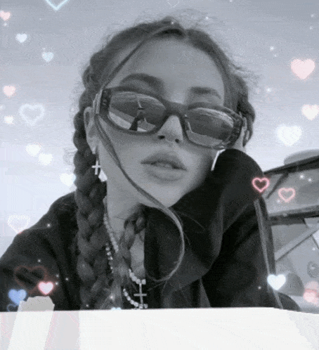 a black and white photo of a woman wearing sunglasses and a cross necklace