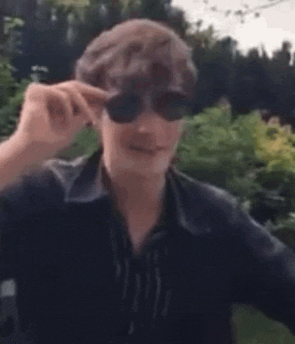 a man wearing sunglasses is making a funny face while talking on a cell phone .