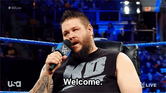 a man in a wrestling ring is holding a microphone and says " welcome "