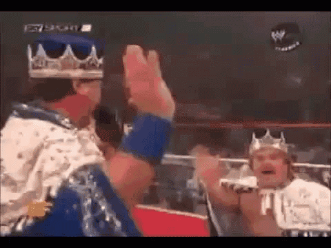 two men wearing crowns are giving each other a high five in a ring .