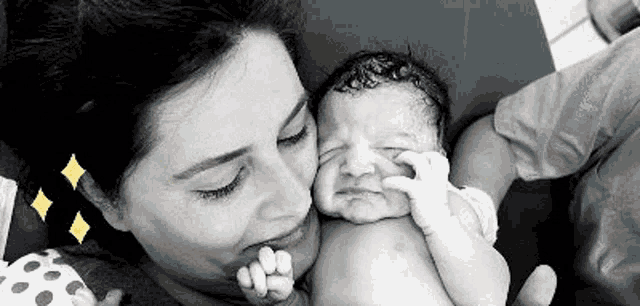 a woman is holding a crying baby in her arms in a black and white photo .