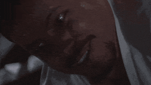 a close up of a man 's face with a white shirt covering his neck