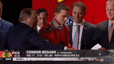 a man in a red jersey is being hugged by a man in a black suit