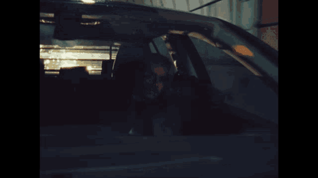a man is sitting in the driver 's seat of a car looking out the window