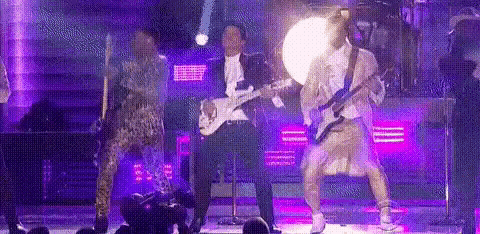 a man is playing a guitar on a stage while a woman is dancing .