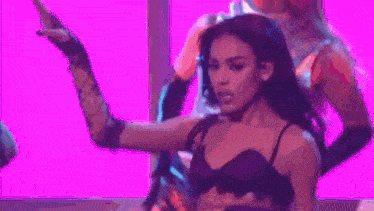 a woman is dancing on a stage in front of a pink background .