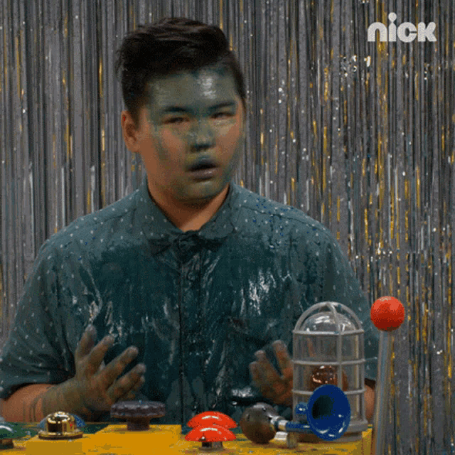 a man with green paint on his face is standing in front of a nick sign