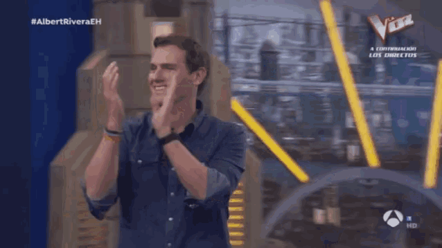 a man is applauding in front of a sign that says la voz