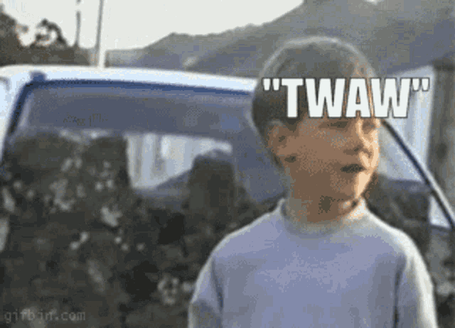 a young boy is standing in front of a car with the words twaw written on his face