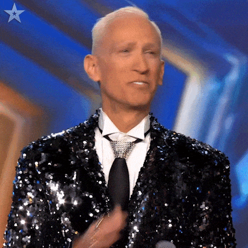 a man wearing a sequined suit and tie is applauding .