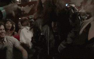 a man in a leather jacket is dancing in a crowd of people in a club .