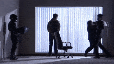 a group of men are standing around a chair in a room