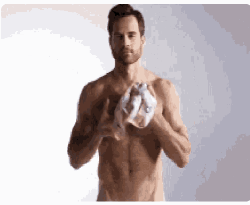 a shirtless man is holding a piece of paper in his hands while standing in front of a white background .