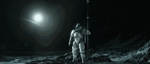 a man in a space suit is standing on the moon with a flag .