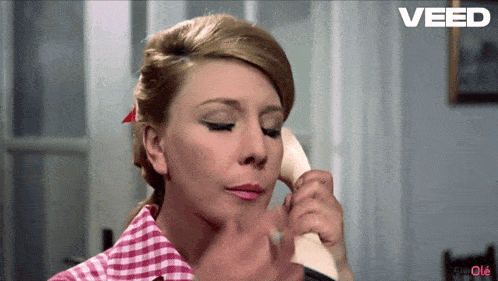 a woman talking on a phone with the word veed on the bottom left