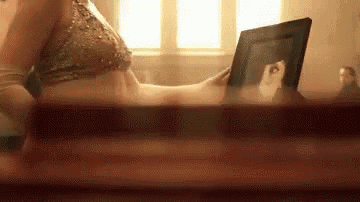 a woman in a bikini is looking at a picture of herself in a frame .