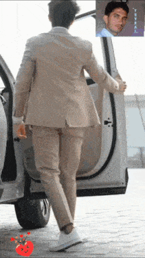 a man in a suit is getting out of a car with a picture of him in the background