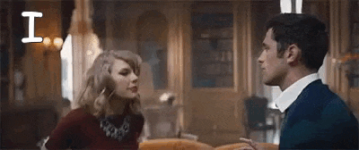 a man and a woman are standing next to each other in a living room and talking to each other .