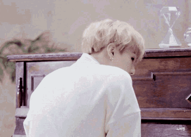 a man in a white shirt is sitting in front of a wooden dresser