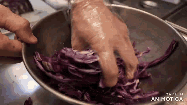 a person is washing purple cabbage in a metal bowl that says made in animatica on the bottom