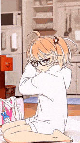 a girl wearing glasses is sitting on the floor in front of a refrigerator
