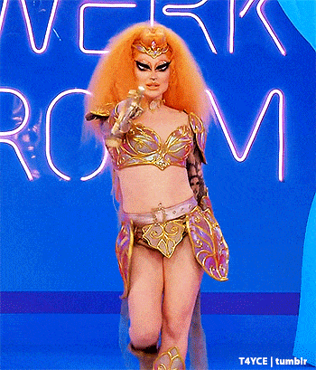 a drag queen with orange hair is standing in front of a neon sign that says work room