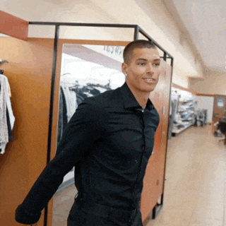a man in a black shirt is standing in a closet