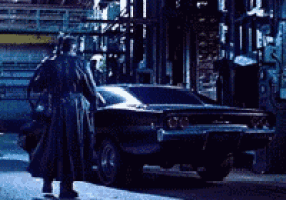 a man in a trench coat is standing next to a car
