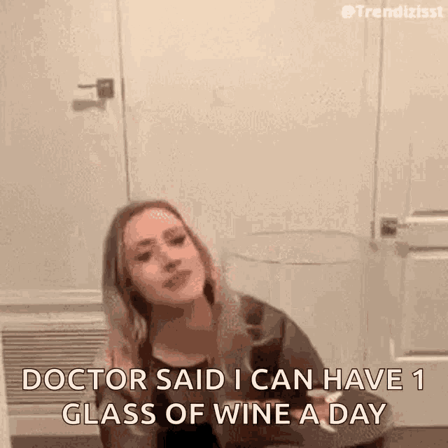 a woman is holding a glass of wine while sitting in front of a door .