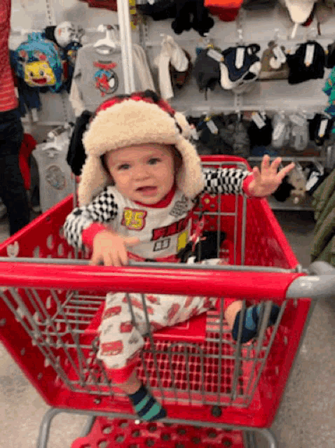 a baby is sitting in a shopping cart wearing a lightning mcqueen outfit
