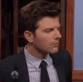a man in a suit and tie is looking at the camera .