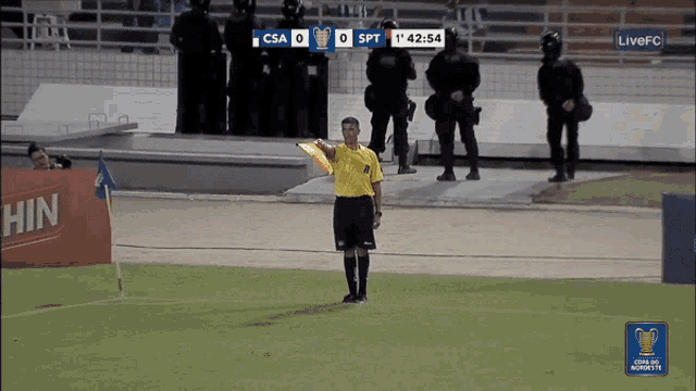 a referee holds up a yellow card in front of a scoreboard that says csa 0 spt 1 42:54