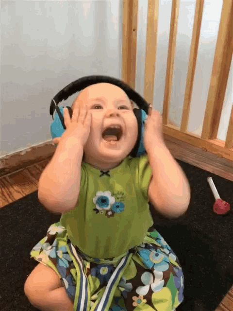 a baby wearing headphones and a green shirt with a flower on it