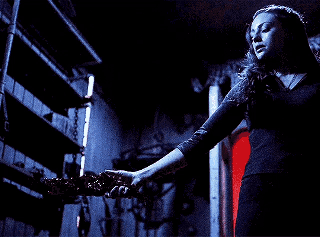 a woman in a black shirt holds a bloody bat in her hand