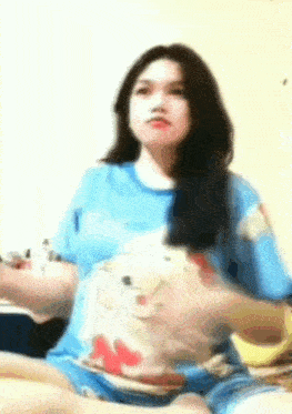 a woman is sitting on a bed wearing a blue shirt with a winnie the pooh on it .