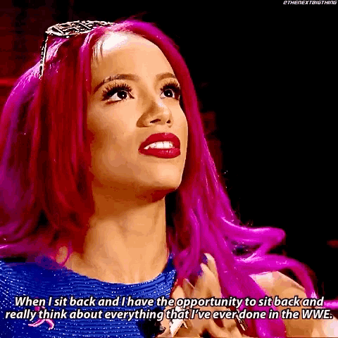 a woman with pink hair is wearing a blue dress and tiara .