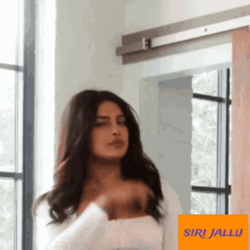 a woman is standing in front of a window with a sign that says siri jallu on it