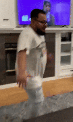 a man is dancing in a living room in front of a television
