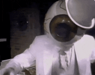 a man in a white suit is wearing a helmet and headphones while playing a keyboard .