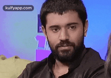 a man with a beard is sitting on a couch .