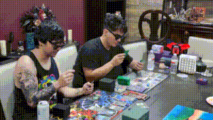 two men are sitting at a table playing a board game .