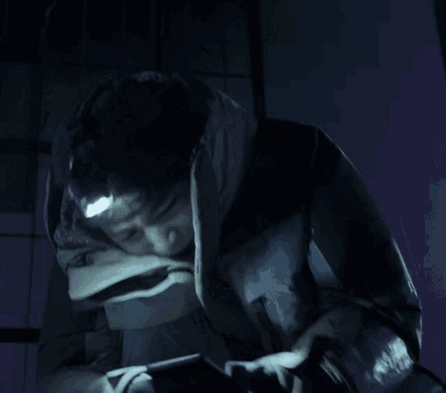 a person wearing a jacket with a hood and a light on their head